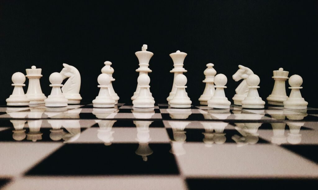 pexels photo 814133 814133 White chess pieces strategically placed on a board reflecting against a black background.
